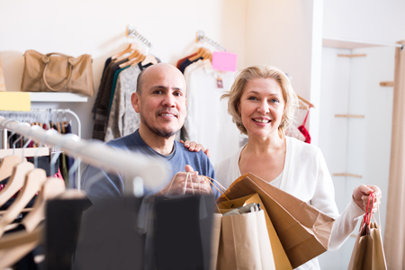 Mature spouses carrying bags with purchases in clothing storeの写真素材