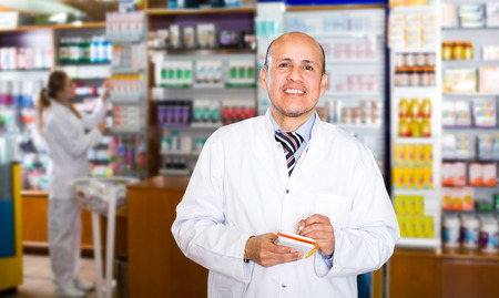 Elderly pharmacist and female assistant working at farmacy receptionの写真素材