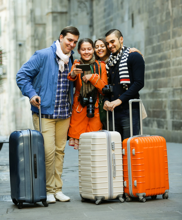 Group of smiling european friends shooting mutual portrait on cell phone outdoorsの写真素材