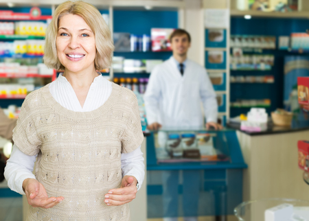 Portrait of happy american mature woman chooses drugs at the pharmacyの写真素材