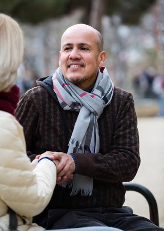 Portrait of happy mature couple having interesting conversation outdoorsの写真素材