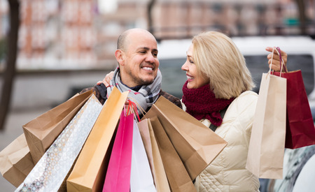 Happy spanish  elderly couple carrying purchases and smiling outdoorsの写真素材