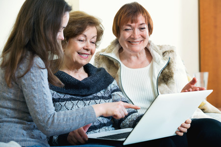 Female pensioners and young relative browsing web on laptopの写真素材