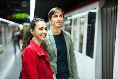 Happy young couple standing at underground station awaiting train. Focus on womenの写真素材