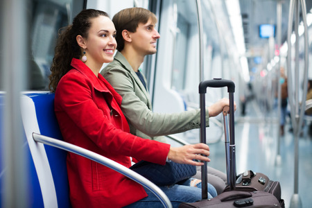 Happy young couple with baggage smiling in subway carの写真素材