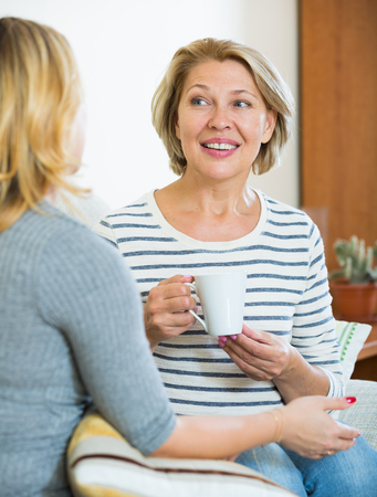 Senior woman and young girl talking and drinking teaの写真素材