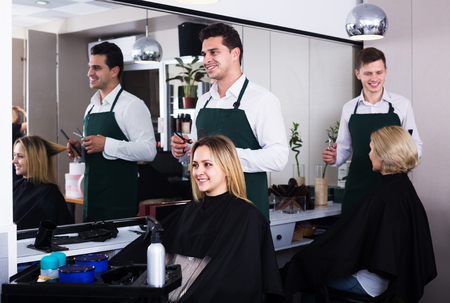 Positive hairdresser cuts hair of blonde girl at the hair salonの写真素材