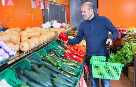 Portrait of mature man purchasing seasonal veggies in farm food storeの写真素材