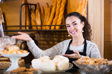 Portrait of caucasian young woman at bakery display with pastryの写真素材