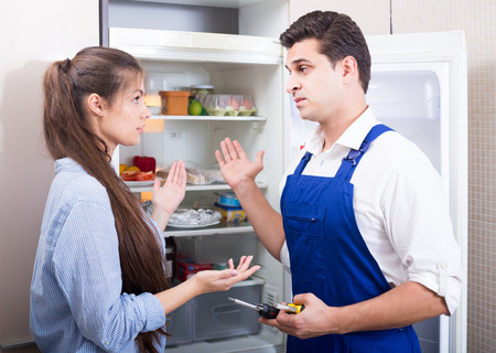 european serviceman asking housewife of technical problems with fridge at homeの写真素材