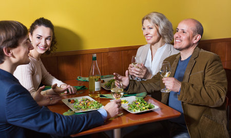 Positive cheerful middle class people enjoying food and wine in cafe