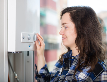 Portrait of ordinary girl using heating water system indoorsの写真素材