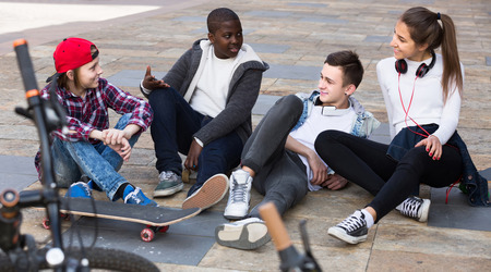 young european  girl and three boys hanging out outdoors and discussing somethingの写真素材
