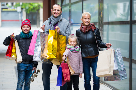 Family couple 40s with kids and shopping bags on city streetの写真素材