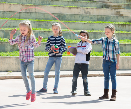 Ordinary girl jumping while jump rope game with friends outdoorの写真素材