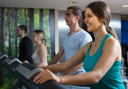 happy  people having running machine class in health club