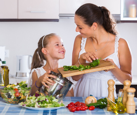 Portrait of smiling woman and little girl cooking vegetablesの写真素材