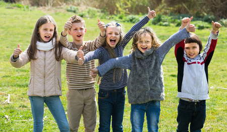 Happy friends having fun and showing thumbs up outdoorsの写真素材