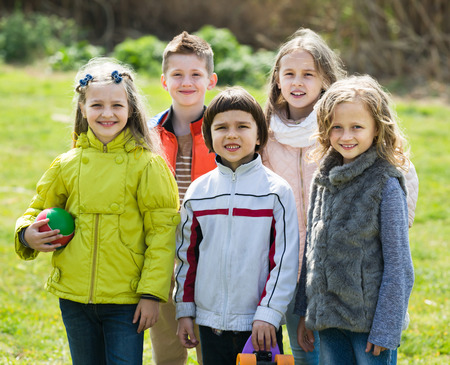 Portrait of happy girls and boys playing in field togetherの写真素材