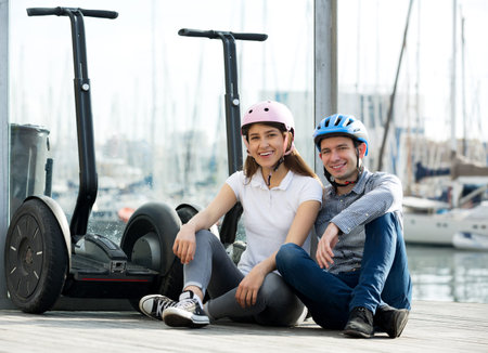 Young couple in love sitting near segways at sea front