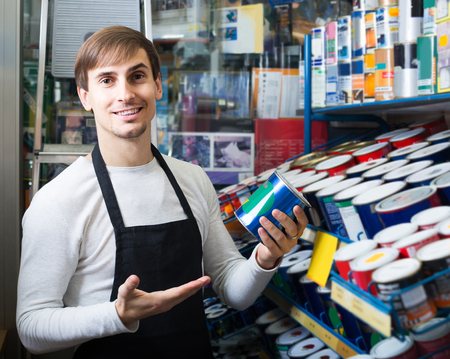 happy russian  shop employee posing near stand with wall paintの写真素材