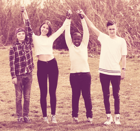Happy young four friends on countryside field in sunny dayの写真素材