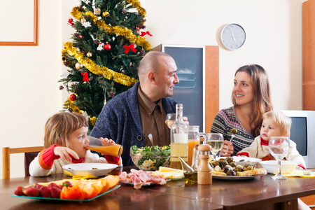 Happy family with two children near Christmas tree  over celebratory tableの写真素材
