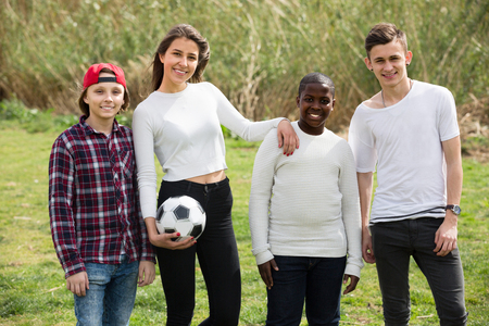 Group of happy teenage friends playing football outdoors in autumn dayの写真素材