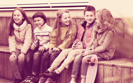 Cheerful junior kids chatting and laughing outdoor in city streetの写真素材