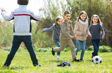 children running after ball in spring parkの写真素材