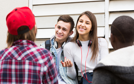 positive american  girl and three boys hanging out outdoors and discussing somethingの写真素材