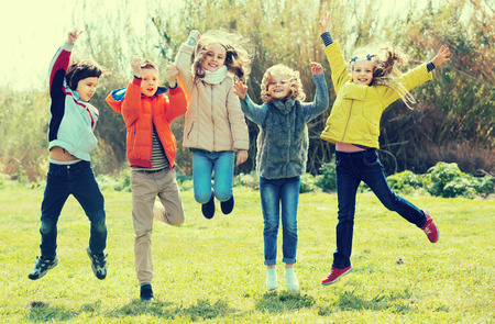 Group of children in high spirits jumping outdoorsの写真素材