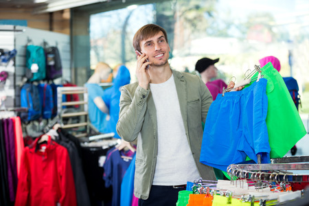 Man gladly speaking on the phone and choosing a sport shortsの写真素材