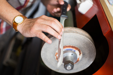 closeup view on a knife being sharpen on the machineの写真素材