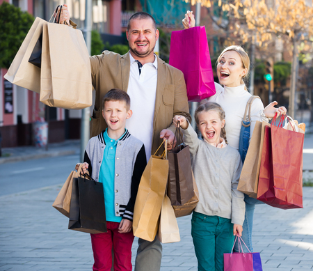 Family smiling and holding shopping bags in the townの写真素材