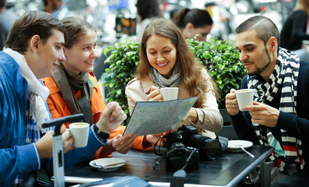adult american tourists drinking coffee at cafe and reading city mapの写真素材