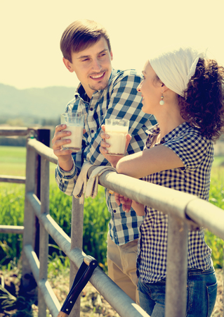 Portrait of cheerful man and woman taking a pause and holding glass with milkの写真素材