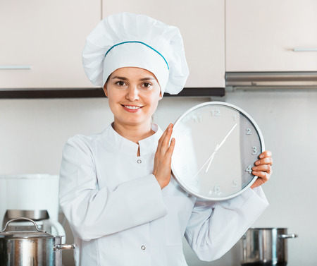 Portrait of  young professional chef holding big clockの写真素材