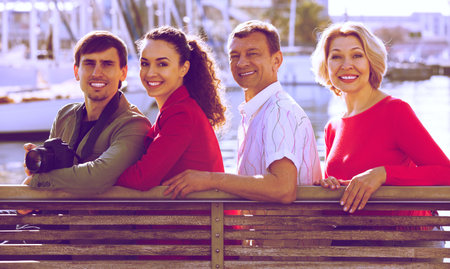 Portrait of positive tourists relaxing on sea front in autumn