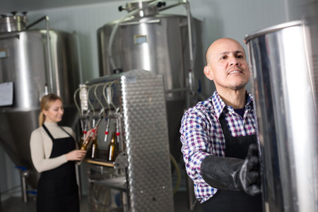 Portrait of mature glad male brewery worker on beer production factory