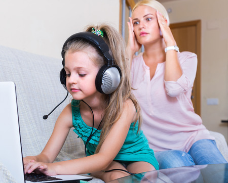 Terrified mother watching daughter using laptop and wifi instead of studyingの写真素材