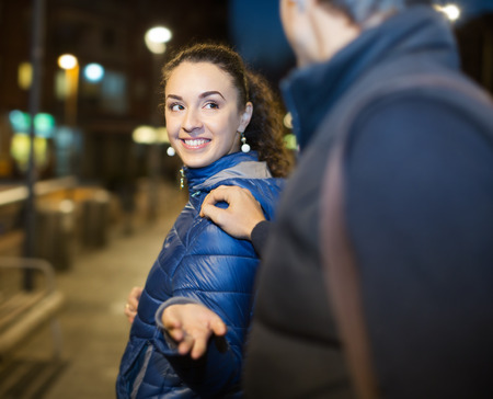 Young brunette woman and hadsome guy meeting at night streetの写真素材