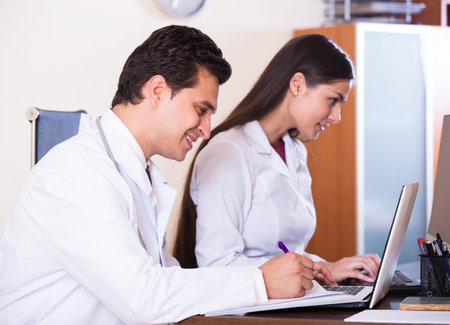 Two professional doctors working together at desk in clinicの写真素材