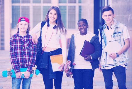 Four smiling young teenage students close to university