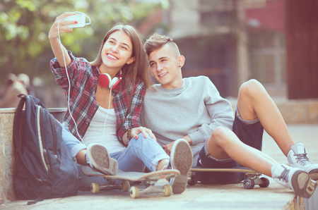 Teenage friends taking photo of themselves for selfie with phoneの写真素材