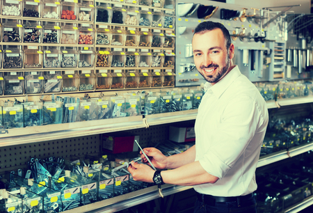 Happy adult man picking plastic dowel from stall in household shopの写真素材