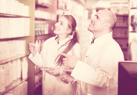 Elderly pharmacist and assistant working at farmacy receptionの写真素材