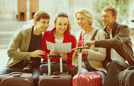 Family of four with luggage checking direction in map outdoorの写真素材
