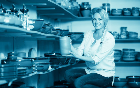 cheerful female customer picking crockery in ceramics workshop