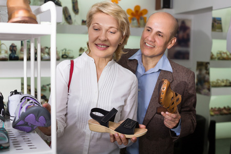 Positive woman over 50 years old choosing pair of comfortable shoesの写真素材